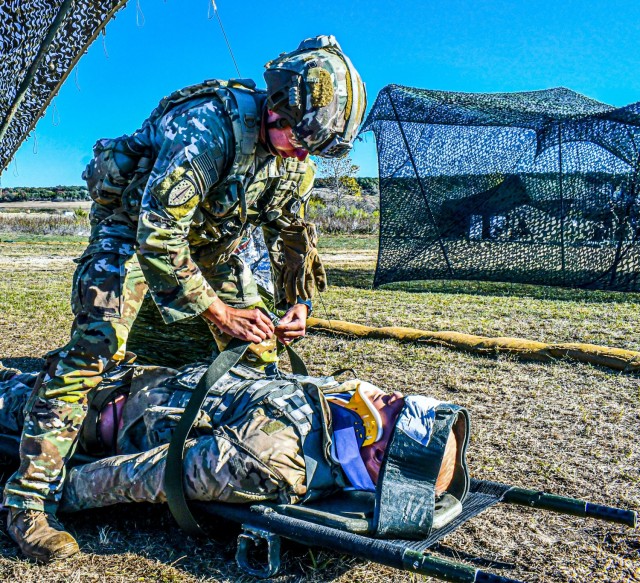 A Soldier secures a medical dummy to a litter as part of the evaluating a casualty task while participating in the Expert Infantryman Badge/Expert Soldier Badge Qualification Course, November 25, 2020, at Fort Hood, TX. The EIB/ESB Qualification...