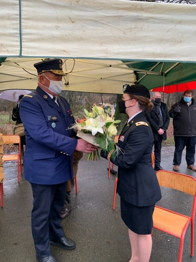 BASTOGNE, Belgium -- Police Commissioner André Mathieu, left, representing the Ardennes police zone, gives flowers to the commander of the SHAPE and Brussels health care facilities, Col. Kathy Spangler, who represented the U.S. Army Nurse Corps,...