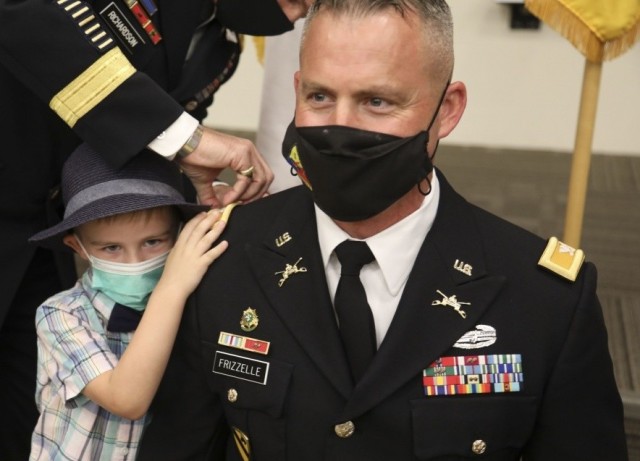 Lt. Col. Bryan W. Frizzelle&#39;s son pins a new shoulder board to his father&#39;s Army Service Uniform coat during a special promotion ceremony held at 1st Armored Division Headquarters at Fort Bliss, Texas Oct. 16, 2020. 