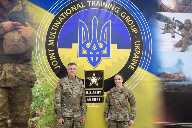 U.S. Army Col. Paul Schmitt and his daughter, Second Lieut. Schmitt, stand in front of a sign for the Joint Multinational Training Group-Ukraine. Schmitt serves as the Army Attaché to the U.S. Embassy in Kviv, Ukraine and is a participant in the...
