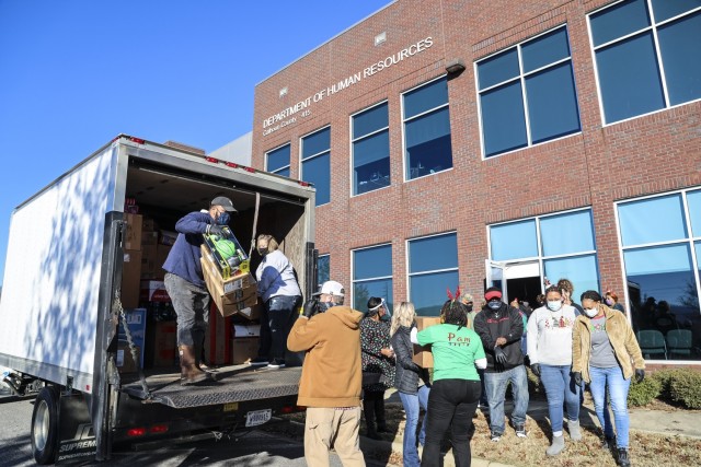 On Dec. 10, Anniston Army Depot employees assist the Department of Human Resources staff in unloading three trucks fill with Christmas gifts for children in the Family Preservation Program.