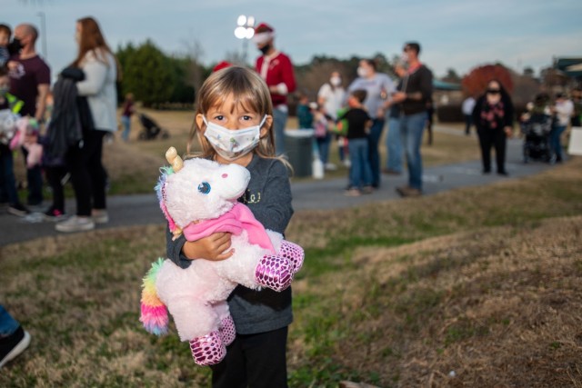 A child holds her unicorn tight as a line forms behind her to meet Santa.