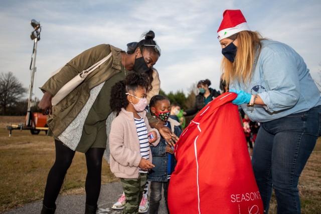 Christine Voegele, one of Santa’s helpers from the Directorate of Family and Moral, Welfare and Recreation hands out gifts to children during the annual Holiday Tree Lighting event Dec. 11.