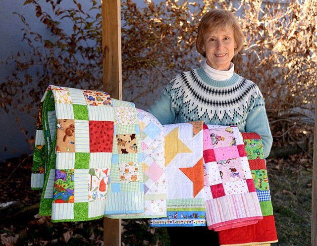 Jeanne Boetig, instructor for the International Military Student Division-sponsored English Language Support Course for international spouses, displays the quilts she made for Project Linus of Greater Kansas City Chapter, which provides handmade...