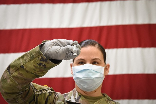 Staff Sgt. Courtney Dunn, an Irwin Army Community Hospital pharmacy technician, rehearses the process of inverting a mock thawed vaccine vial gently 10 times before dilution, according to a manufacturer’s COVID-19 vaccine product. Vials are...