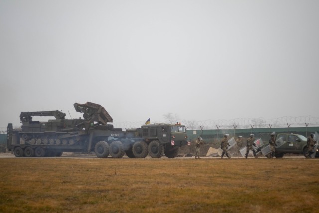 Soldiers with Troop B, 1st Squadron, 113th Cavalry Regiment, Iowa Army National Guard, escort a BAT-2 armored tracklayer during obstacle and barrier removal training at Camp Marechal de Lattre De Tassigny in Kosovo on Dec. 16, 2020. Soldiers with the Ukrainian Freedom of Maneuver Detachment operated the vehicle while U.S. Soldiers provided crowd and riot control support throughout the training exercise in support of NATO’s Kosovo Force, a peacekeeping organization dedicated to maintaining stability in the region. (U.S. Army National Guard photo by Sgt. Zachary M. Zippe)