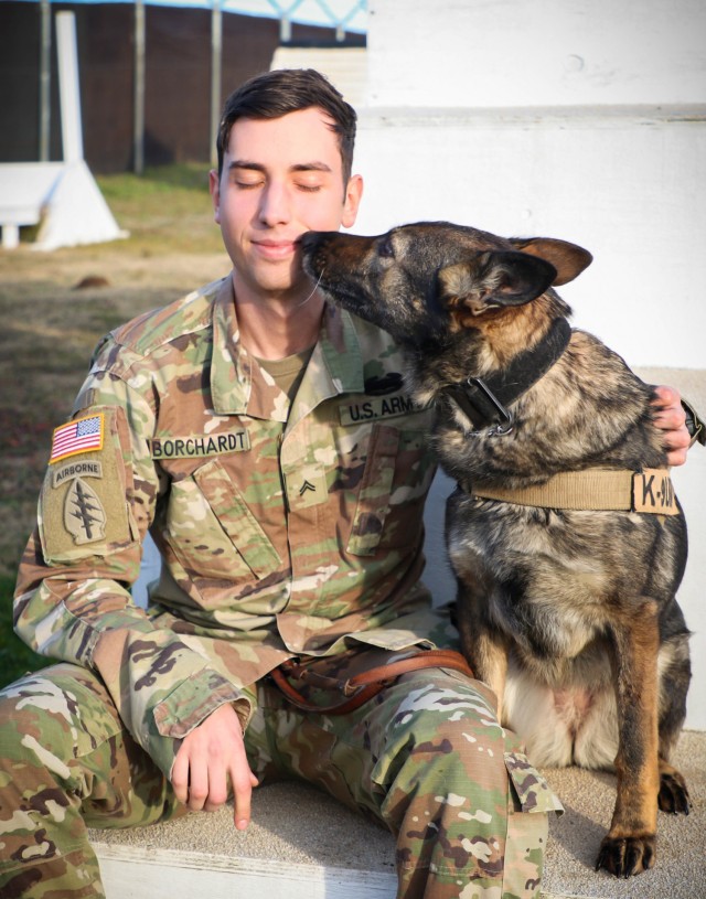 U.S. Army Cpl. Dustin Borchardt, a military dog handler with the 100th Military Police Detachment based out of Stuttgart, Germany, poses with his military working dog named Pearl at Camp Bondsteel, Kosovo, on Dec. 8, 2020. Borchardt and Pearl have been working together for over six years, and are currently serving in Kosovo Force, Regional Command East, a NATO led organization dedicated to the safety and security of all people in Kosovo. In support of the KFOR mission, the pair conducts routine searches of vehicles entering Camp Bondsteel and participates in local community engagements to share knowledge with the public. 