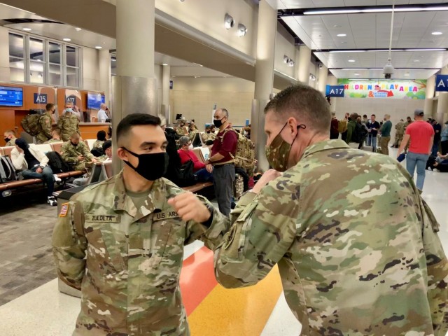 Pvt. Luis Zuloeta, a 68W Combat Medic who just graduated from the U.S. Army Medical Center of Excellence (MEDCoE) is greeted by CSM Clark Charpentier with a COVID appropriate elbow bump as he awaits travel home to New Jersey for Holiday Block Leave at the San Antonio International Airport on December 19, 2020.