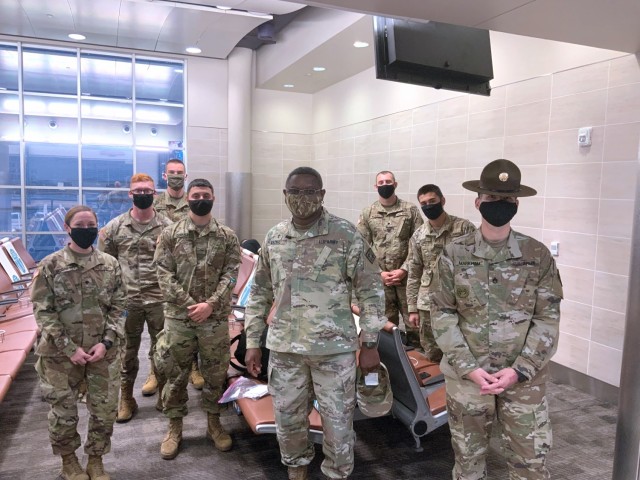 Drill Sergeant Jeffrey Markham (far right) and Chaplain (Maj.) Oyedeji Idowu (center) speak with Soldiers in training at the U.S. Army Medical Center of Excellence as they await flights from the San Antonio International Airport for Holiday Block Leave on December 19, 2020.