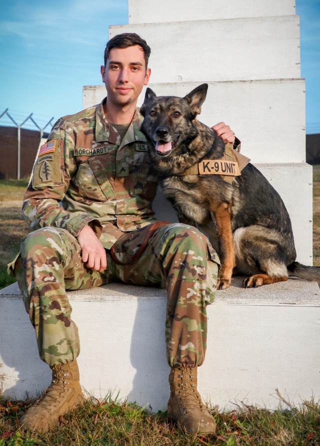 U.S. Army Cpl. Dustin Borchardt, a military dog handler with the 100th Military Police Detachment based out of Stuttgart, Germany, poses with his military working dog named Pearl at Camp Bondsteel, Kosovo, on Dec. 8, 2020. Borchardt and Pearl have been working together for over six years, and are currently serving in Kosovo Force, Regional Command East, a NATO led organization dedicated to the safety and security of all people in Kosovo. In support of the KFOR mission, the pair conducts routine searches of vehicles entering Camp Bondsteel and participates in local community engagements to share knowledge with the public.