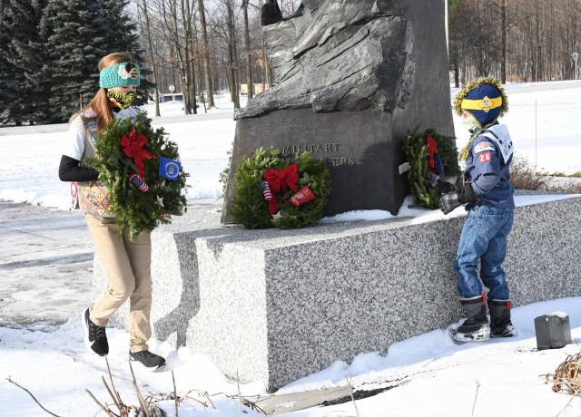 Scouts from the Fort Drum Cub Scout Pack 26 and Girl Scouts Service Unit 512 place wreaths at the Military Mountaineers Monument and the surrounding markers in Memorial Park on Dec. 19. On National Wreaths Across America Day, ceremonies are conducted across the country to honor fallen service members, and this was the second year that Fort Drum Scouts participated in the event. (Photo by Mike Strasser, Fort Drum Garrison Public Affairs)
