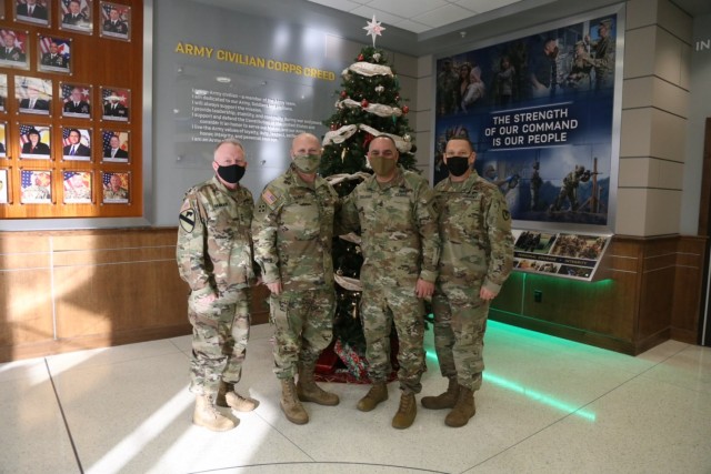 Lt. Gen. Douglas M. Gabram, Commanding General of U.S. Army Installation Management Command, is joined by Gen. Edward Daly, Commanding General of Army Materiel Command, Cmd. Sgt.’s Maj. Alberto Delgado and Joe Ulloth, the senior enlisted leaders for AMC and IMCOM, in front of the Christmas tree in the lobby of IMOCM headquarters Dec. 17, 2020.  