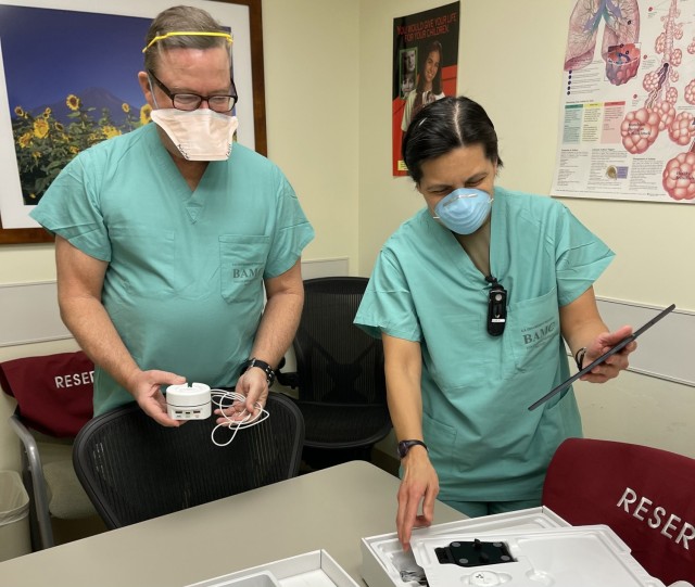 Mike Lavers, sleep technician, and Sgt. 1st Class Annabelyn Verdeflor, noncommissioned officer in charge of the Pulmonary Clinic, look over the components of a home healthcare kit as part of the COIVD-19 Remote Monitoring Program, a joint effort...