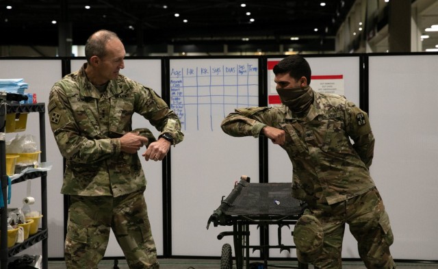 U.S. Army Lt. Gen. Randy A. George, commanding general of I Corps, bumps elbows with Spc. Richard Pinero, a Combat Medic Specialist assigned to 10th Field Hospital, after giving him a coin in Seattle, April 7, 2020. Soldiers from the 10th Field...