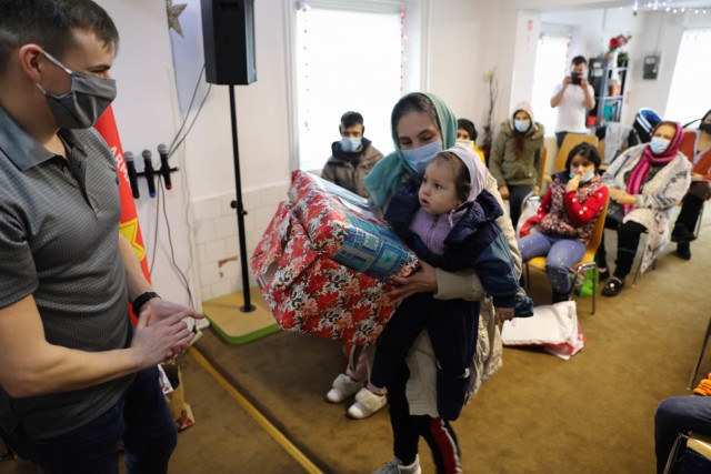 BUCHAREST, Romania – Sgt. Garrett Montalvo, Civil Affairs Sgt., Civil Affairs Team 3231, 432nd Civil Affairs Battalion, Green Bay, Wis., hands Christmas presents to a small child and her grandmother here on Dec. 21. Through the combined efforts...