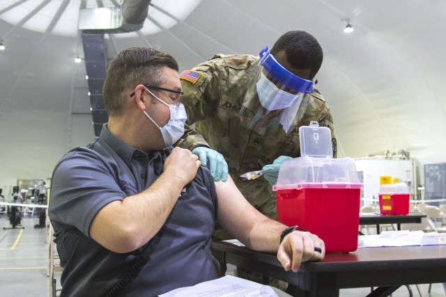 Dr. Andrew Bloom, the emergency medical services director of Fort Riley receives the Moderna vaccine from Sgt. Jason Johnson, a medic at the Irwin Army Community Hospital on December 23 on Fort Riley, Kansas. The Moderna vaccine will be offered to healthcare professionals first.