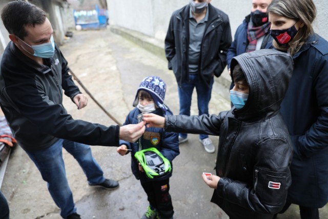 BUCHAREST, Romania – Roxy Sandu, Regional Leader, Salvation Army, Romania looks on as Capt. Greg Caruso Team Chief, Civil Affairs Team 3231, 432nd Civil Affairs Battalion, Green Bay, Wis., gives two brothers U.S. Army rank patches and U.S. and...