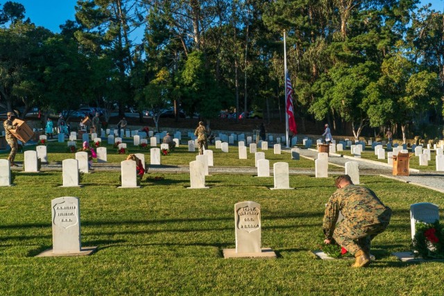 Service members adorning graves with holiday wreaths at the Presidio of Monterey cemetery during the fourth annual Wreaths Across America event on Saturday, December 19.