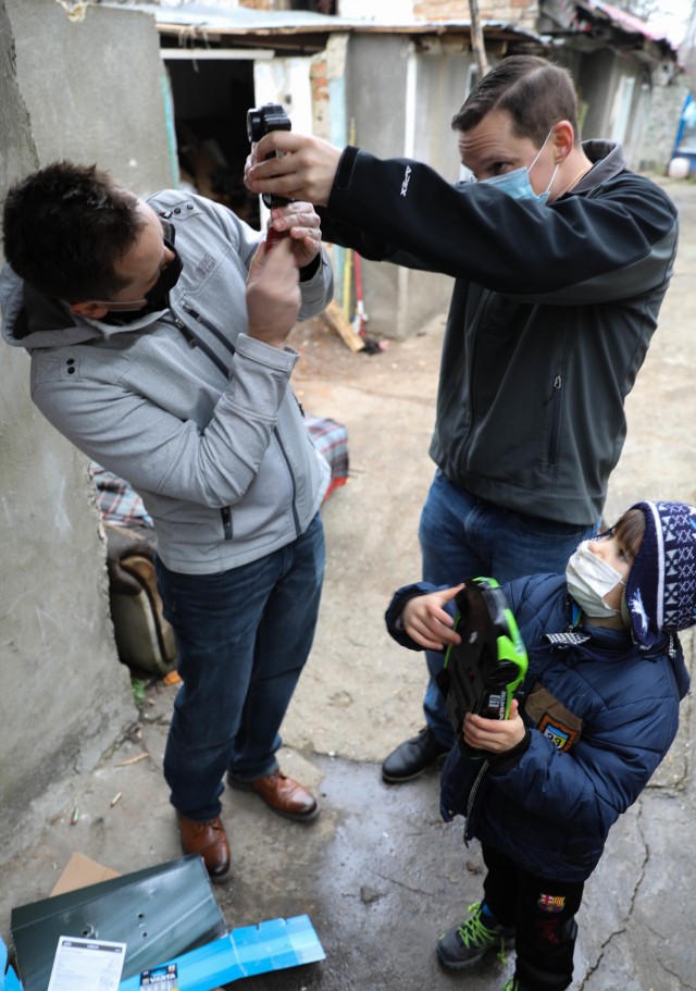 BUCHAREST, Romania – Sgt. 1st Class Isaac Armstrong, Team Sgt., and Capt. Greg Caruso Team Chief , Civil Affairs Team 3231, 432nd Civil Affairs Battalion, Green Bay, Wis., help a child put batteries in the remote control for his new toy car here...