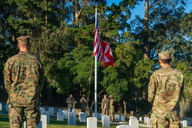 A Marine and a Soldier watching the American and Gold Star flag being lowered at the Presidio of Monterey cemetery during the fourth annual Wreaths Across America event on Saturday, December 19.