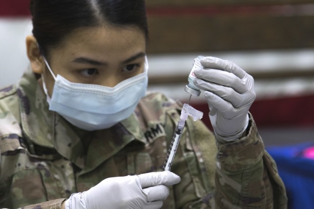 Spc. Maria Ecle, a pharmacist technician at the Irwin Army Community Hospital prepares the Moderna vaccine for injection December 23 on Fort Riley, Kansas. The injection will be the first dose to be administered on Fort Riley.