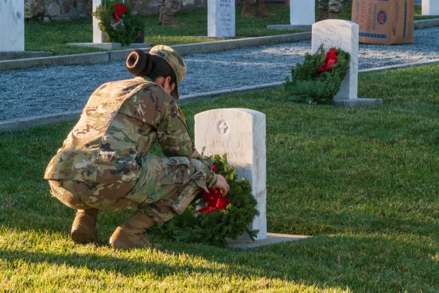 A Soldier adorning a grave with a holiday wreath at the Presidio of Monterey cemetery during the fourth annual Wreaths Across America event on Saturday, December 19.
