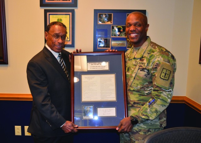 Retired Command Sgt. Maj. Milton B. Hazzard presents a framed memento courtesy of Gen. Bruce C. Clarke to CSM Sean Rice, Quartermaster Corps CSM, during an informal presentation March 15 in the Hazzard Conference Room located at Mifflin Hall....