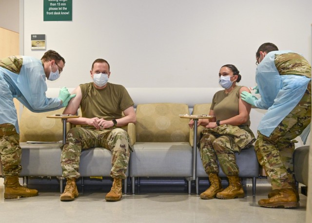 U.S. Army Lt. Col. Adam Cronkhite (seated left), Director of Emergency Services, and U.S. Army Lt. Col. Maria Bruton (seated right), commander of U.S. Army Health Clinic Stuttgart, simultaneously were the first to receive the COVID-19 vaccine in...