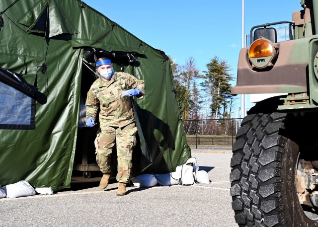 Spc. Madalyn Stella, combat medic, 197th Field Artillery Brigade, New Hampshire Army National Guard, emerges from a medical tent with a COVID-19 vaccine for a waiting patient Dec. 29 in Exeter, N.H. Stella is one of 11 New Hampshire Guard members...