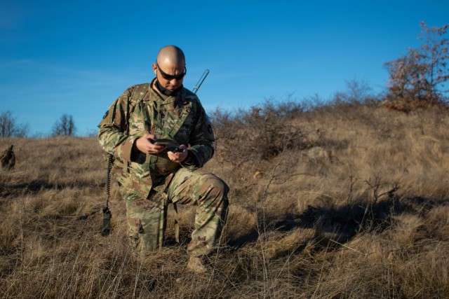 Sgt. 1st Class Brandon Carley, a pathfinder assigned to Kosovo Force, Regional Command-East, maintains communications during a helicopter landing site clearance operation in Kosovo on Dec. 23, 2020. The UH-60 Black Hawk pilots dropped off the...