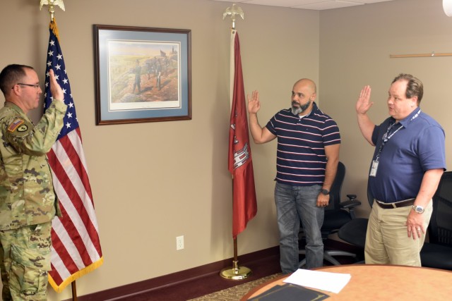 Col. Karl Jansen, U.S. Army Corps of Engineers St. Paul District Commander, administers the oath of office to St. Paul District civil engineers Omar Shalham and Troy Tooz, at the western area office in Fargo, North Dakota, June 11