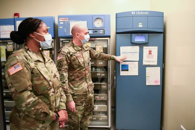 U.S. Army Health Center Vicenza Pharmacy Officer in Charge Maj. Sean O'Brien and Noncommissioned Officer in Charge Sgt. La'Terra Cook explain the subzero freezer will maintain the COVID-19 vaccine within appropriate temperature controls December...