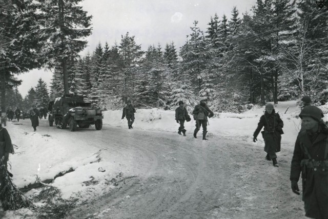 Soldiers with the Army&#39;s 17th Airborne Division walk ahead of a military vehicle on a snow-covered road near Houffalize, Belgium, in January 1945.