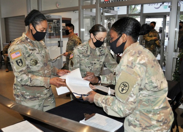 Command Sgt. Maj. Tanya Boudreaux, left, command sergeant major of U.S. Army Medical Department Activity ̶ Japan, and Col. Tanya Peacock, center, commander of MEDDAC ̶ J, turn in their questionnaires before receiving COVID-19 vaccine shots at...