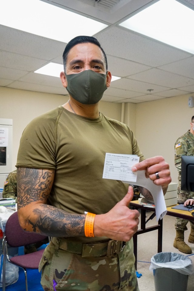 Command Sgt. Maj. Alex Kupratty, command sergeant major of the 4th Infantry Brigade Combat Team (Airborne), 25th Infantry Division, “Spartan Brigade,” shows off the orange wristband showing the time he received his initial dose of the Pfizer COVID-19 vaccine Jan. 6, 2021, Joint Base Elmendorf-Richardson. The first troops in the Spartan Brigade to receive the vaccine were medics, physicians, key leaders and other designated volunteers that would likely deploy first in an emergency.