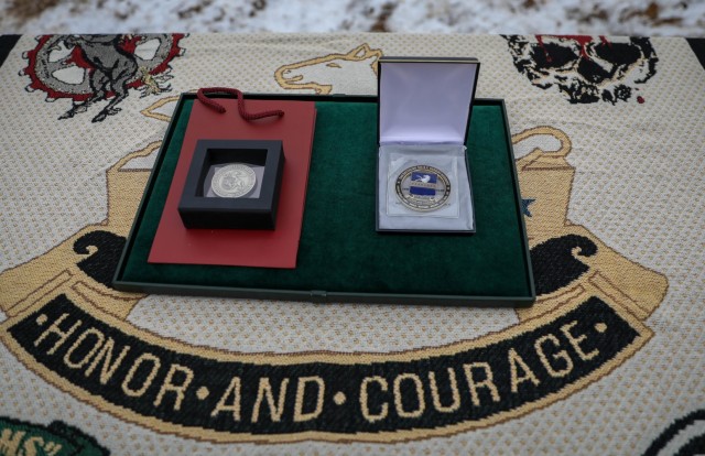 Challenge coins from Lithuania’s Minister of Defense, left, and 2nd Battalion, 8th Cavalry Regiment, 1st Armored Brigade Combat Team, 1st Cavalry Division, right, are displayed on a tray during a small, socially distanced color uncasing ceremony...