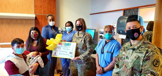 Sgt. Alan Delcid, Quetzali Gisselle Delcid Juarez and baby Landon pose with BMACH Commander Col. Melissa Hoffman and Command Sgt. Maj. Hector Santiago-Perez after receiving an AAFES gift certificate celebrating 2021's first baby.