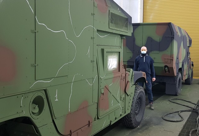 Alessio Maenza, a painter from the Directorate of Maintenance, Army Field Support Battalion – Africa, 405th Army Field Support Brigade, stands next to one of the dozens of military vehicles he re-painted. The vehicles are part of Army...