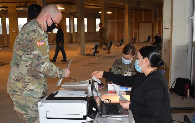 MONS, Belgium – Sgt. Andrew Petersen, left, biomedical equipment technician at SHAPE Healthcare Facility, fills out paperwork to receive a COVID-19 vaccination at the healthcare facility Jan. 8 at Mons, Belgium. The SHAPE Healthcare Facility and...