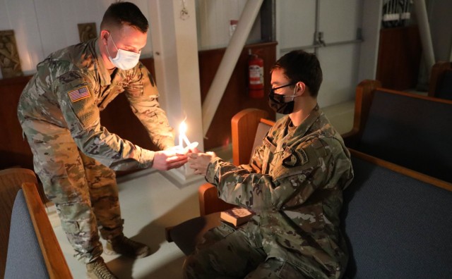 MIHAIL KOGALNICEANU, Romania – Spc. Joshua Smith, Area Support Group-Black Sea, Religious Affairs non-commissioned officer in charge, Alabama National Guard, lights a candle for PFC Evan Hooper, who participated in the Christmas Eve Service...