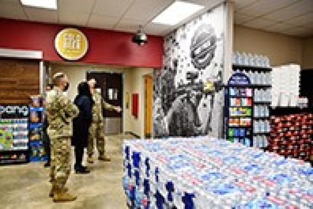 Col. Ryan K. Roseberry, garrison commander (right) talks with Ruth Shepherd, Express 3 store manager (center), about the large photo of a Fort Polk Soldier in training as Command Sgt. Maj. Christopher M. Ausbun, garrison command sergeant major,...