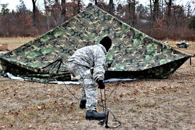 A Fort McCoy Cold-Weather Operations Course (CWOC) Class 21-01 student helps set up an Arctic 10-person tent Dec. 15, 2020, at a South Post training area at Fort McCoy, Wis. CWOC students are trained on a variety of cold-weather subjects, including snowshoe training and skiing as well as how to use ahkio sleds and other gear. Training also focuses on terrain and weather analysis, risk management, cold-weather clothing, developing winter fighting positions in the field, camouflage and concealment, and numerous other areas that are important to know in order to survive and operate in a cold-weather environment. The training is coordinated through the Directorate of Plans, Training, Mobilization and Security at Fort McCoy. (U.S. Army Photo by Scott T. Sturkol, Public Affairs Office, Fort McCoy, Wis.)