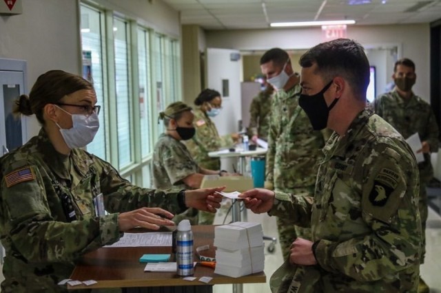 U.S. Army Maj. Jade Snader, left, chief nurse for Soldier Health Services, Blanchfield Army Community Hospital, gives 1st Sgt. David Wasierski, right, Headquarters and Headquarters Company "King of Clubs", 1st Brigade Combat Team "Bastogne", 101st Airborne Division (Air Assault), a COVID-19 Pfizer BioNtech vaccine information card during his screening prior to being vaccinated. (U.S. Army photo by Maj. Vonnie Wright)