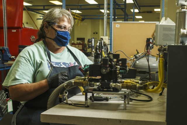 Martha Hunter, a pneudraulics mechanic at Anniston Army depot, connects a hydraulic component to a testing apparatus for a Stryker vehicle. (U.S. Army photo by Mark Cleghorn)
