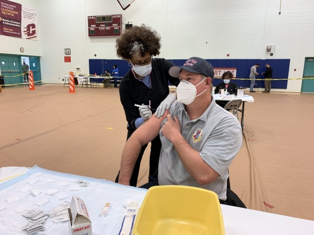 Darcel Spragley, a registered nurse at Kenner Army Health Clinic, administers the first COVID-19 vaccination on Fort Lee to Neal Hudgins, a Fire Department captain, Monday at Clark Fitness Center.  All this week, healthcare providers and medical...