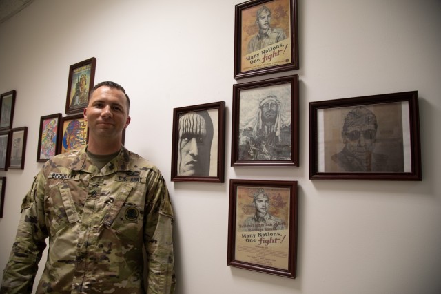 Sgt. 1st Class Brandon Brouillet assigned to Headquarters and Headquarters Battery, 11th Air Defense Artillery Brigade, poses with artwork depicting Native American Heritage, Jan. 11, 2021, at Al Udeid Air Base. (U.S. Army photo by Staff Sgt. Mariah Jones)