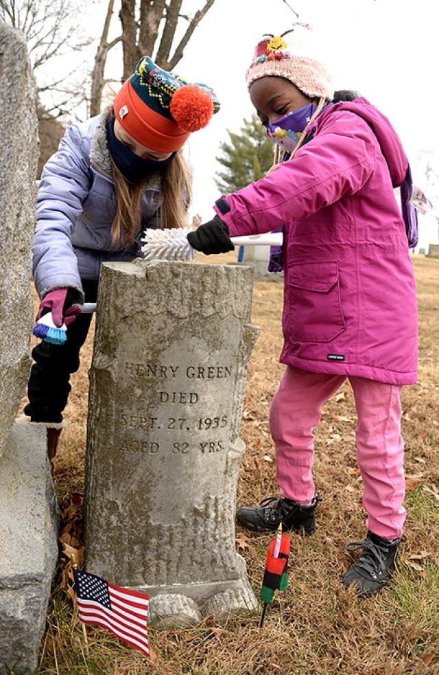 Nine-year-old Sloane Pittman and 7-year-old Yana Elston clean the grave marker for Henry Green, who died in 1935 at the age of 82, and the joint marker for John Burley, 1841-1909; Laura Caldwell, 1865-1917; and Addie Green, 1858-1921, as...