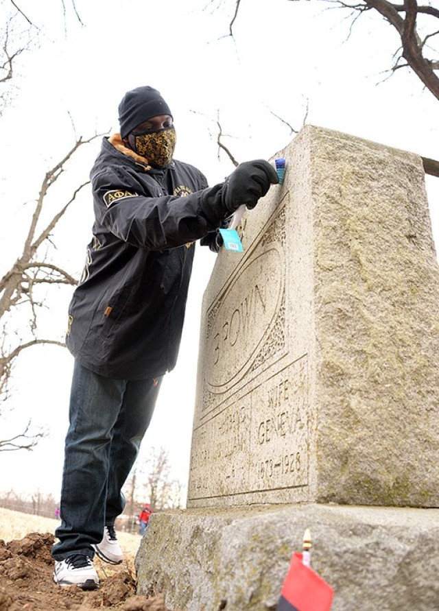 Volunteer Lt. Col. Michael Sturdivant, a knowledge manager for the Joint Center for International Security Force Assistance, cleans the gravestone for William Brown's wives — Elenora Brown, born 1856 and died 1912; and Geneva Brown, born 1873...