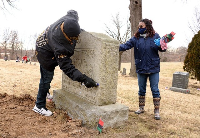 Volunteers Lt. Col. Michael Sturdivant, a knowledge manager for the Joint Center for International Security Force Assistance, and Lauren Cooper clean the gravestone for William Brown's wives — Elenora Brown, born 1856 and died 1912; and Geneva...