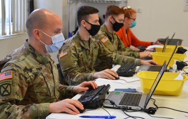 U.S. Army Health Center Vicenza Pharmacy Officer in Charge Maj. Sean O'Brien (left) and other staff members check reservations made for flu vaccinations Jan. 15, 2021, on Caserma Ederle. 
...